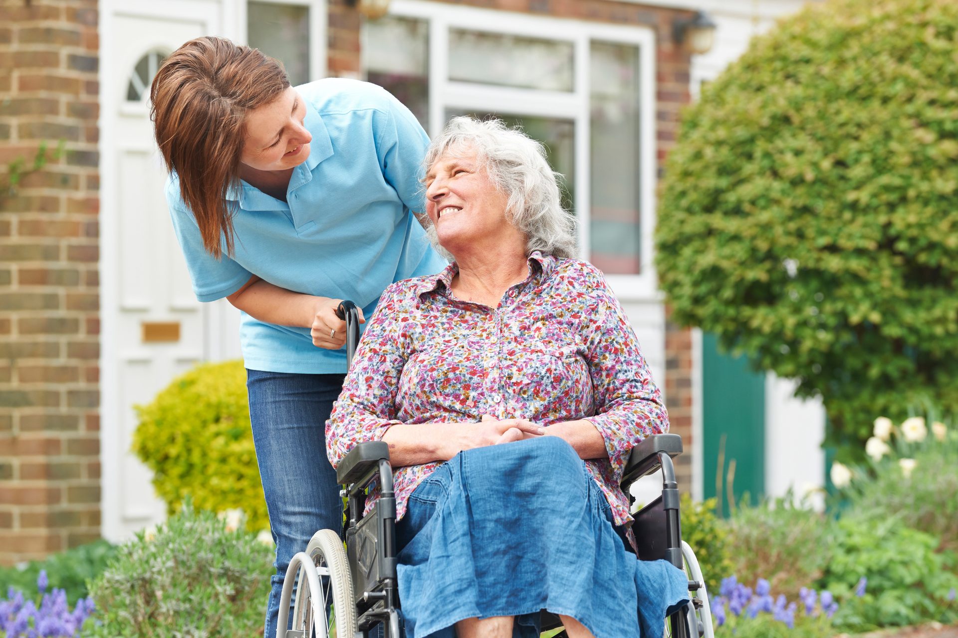 Caregiver folding laundry while an older man reads in his living room